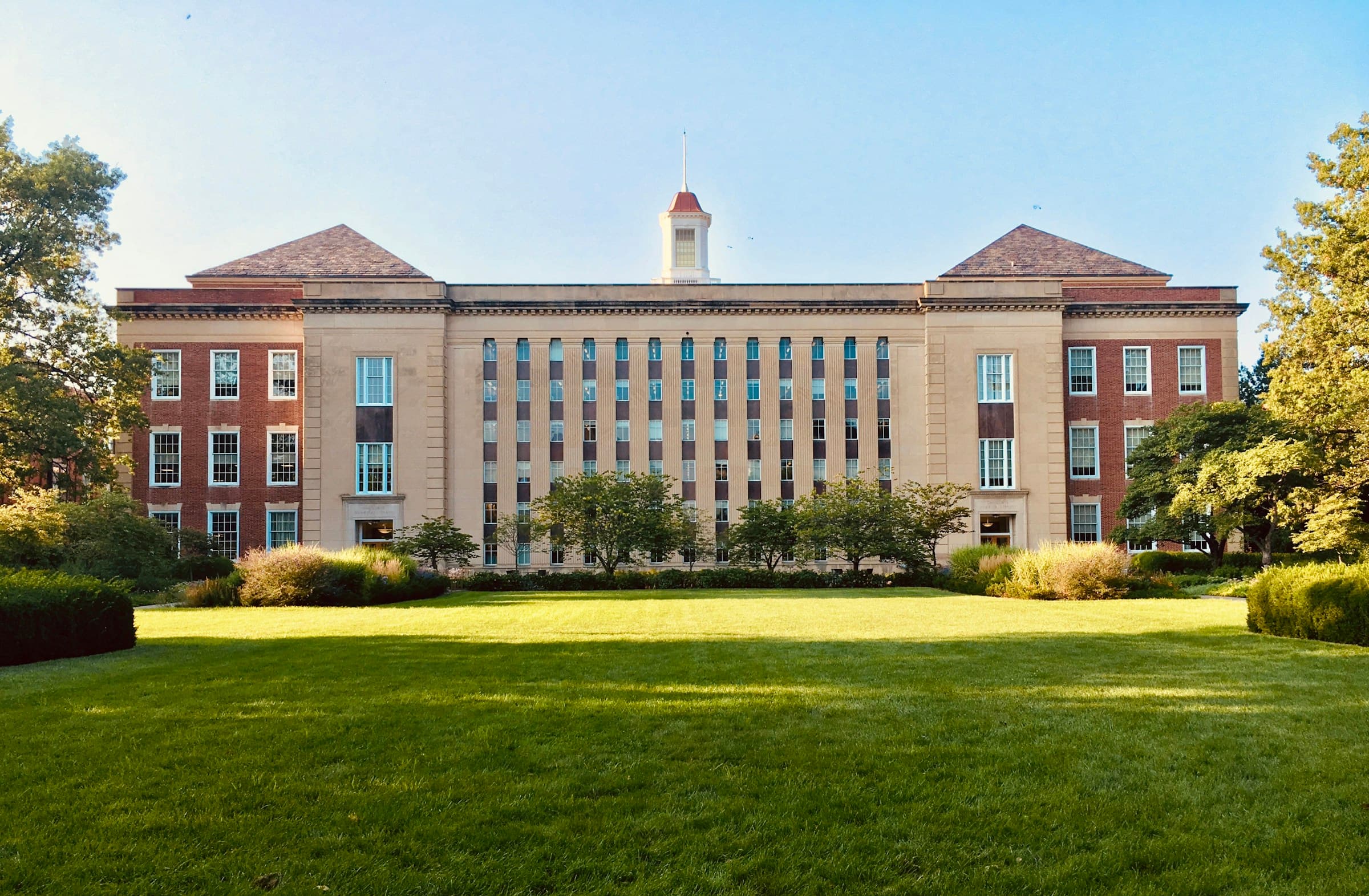 Brick and stone campus building behind a wide lawn